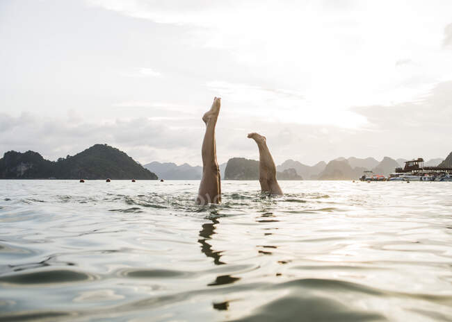 Pareja haciendo handstand en aguas de Ha Long Bay, Vietnam - foto de stock
