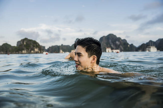 Hombre nadando en aguas de Ha Long Bay, Vietnam - foto de stock