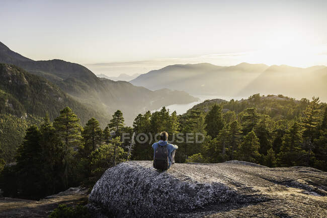Hombre sentado en la roca, mirando a la vista, Jefe Stawamus, mirando - foto de stock