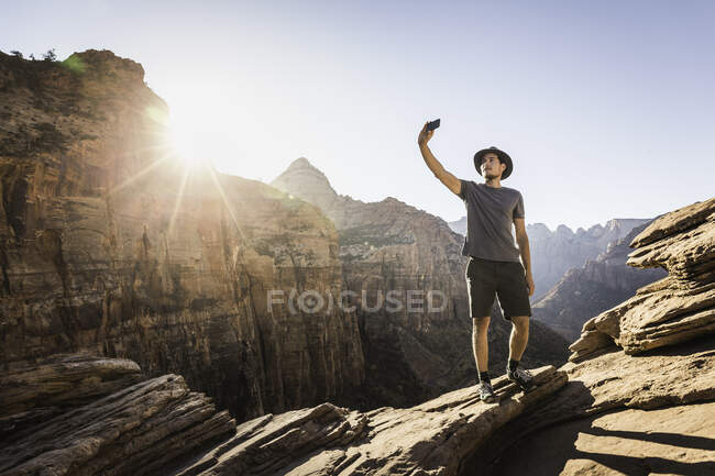 Mann steht auf Felsen, macht Selfie, benutzt Smartphone, Zion Nati — Stockfoto