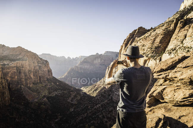 Homem em pé na montanha, fotografando, vista Parque Nacional de Zion — Fotografia de Stock