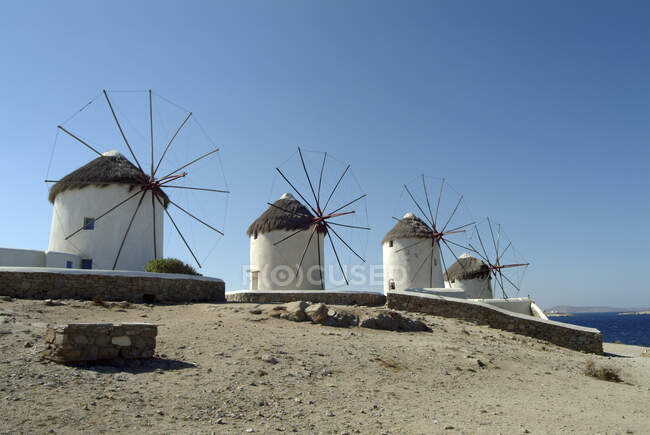 Hilera de molinos de viento tradicionales en la playa, Mykonos, Cyclades, Grecia - foto de stock