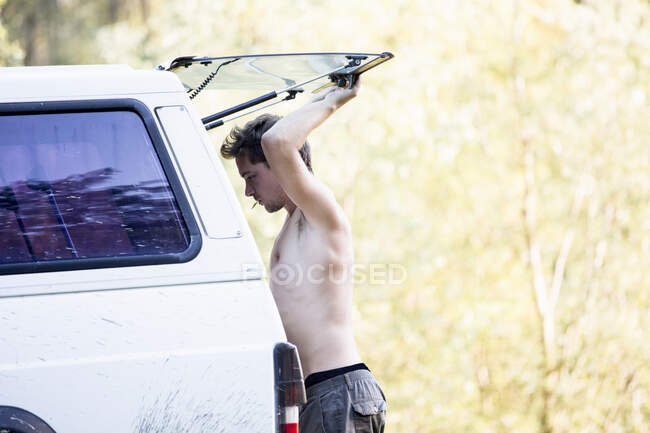 Mann hält hintere Scheibe von Fahrzeug im Park hoch — Stockfoto