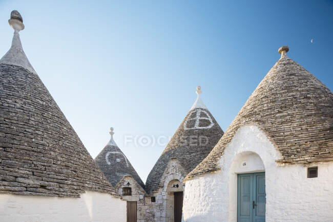 Vier weiß getünchte Trullo-Häuser mit konischen Dächern, Alberobello, — Stockfoto