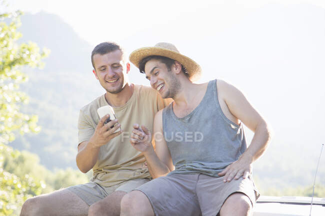 Мужчины, использующие мобильный телефон на крыше автомобиля — стоковое фото