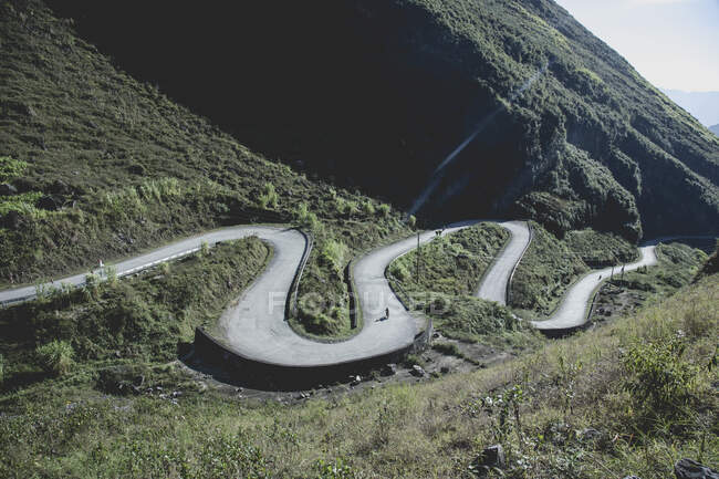 Estrada sinuosa através de montanhas, motocicletas à distância, Vietnã — Fotografia de Stock