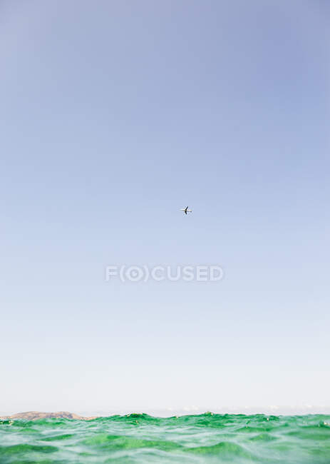 Самолет, летящий в голубом небе над морем, Кальви, Корсика, Франция — стоковое фото
