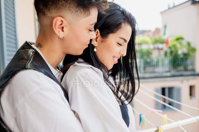 Portrait de jeune couple lesbien debout sur le balcon, étreignant. — Photo de stock