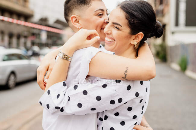 Retrato de una joven pareja lesbiana de pie al aire libre, abrazándose. - foto de stock