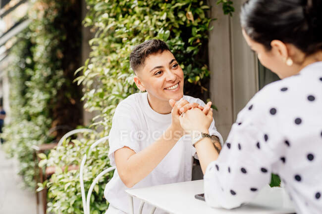 Молода пара лесбіянок сидить на відкритому повітрі в кафе, посміхаючись один одному — стокове фото