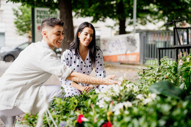 Jovem casal lésbico em pé no mercado stall, olhando para as plantas — Fotografia de Stock