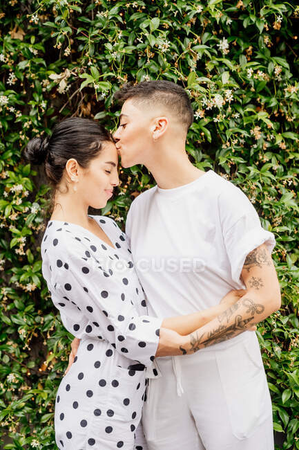 Retrato de jovem casal lésbico em pé ao ar livre, abraçando e beijando — Fotografia de Stock