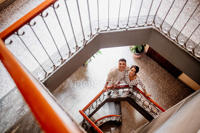 High angle view of young lesbian couple standing at bottom of stairwell, looking at camera — Stock Photo