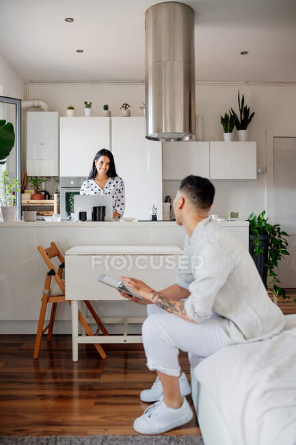 Young lesbian couple in modern apartment, smiling at each other. — Stock Photo