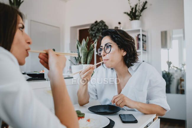 Дві жінки з коричневим волоссям сидять за столом, їдять суші . — стокове фото