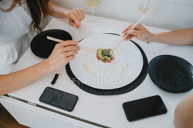 High angle close up of two women sitting at a table, eating sushi. — Stock Photo