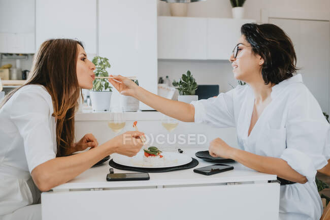 Deux femmes aux cheveux bruns assises à une table, mangeant des sushis. — Photo de stock
