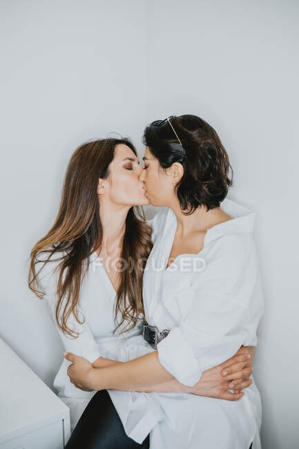 Портрет двух женщин с каштановыми волосами, обнимающих и целующихся. — стоковое фото