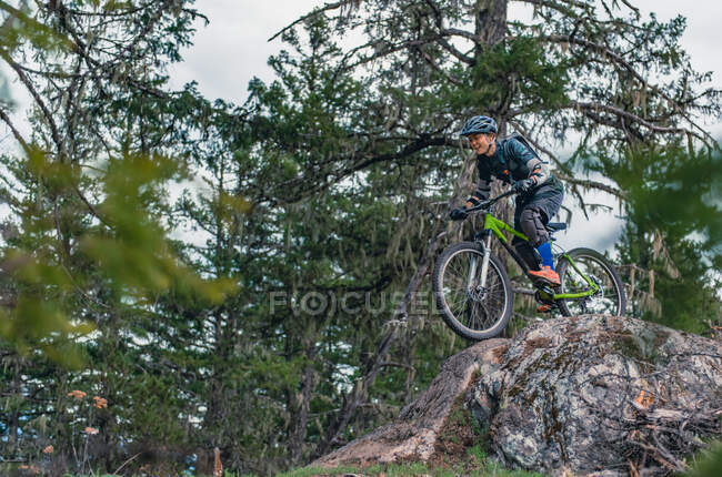 Femme en vélo de montagne dans une forêt dans les montagnes canadiennes — Photo de stock
