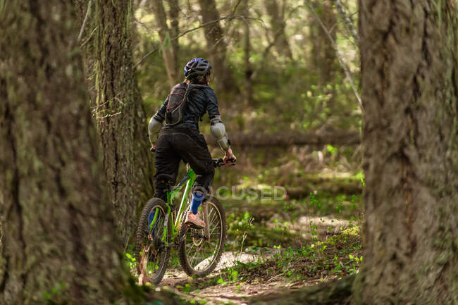 Woman mountain-biking in a forest in the Canadian mountains — Stock Photo