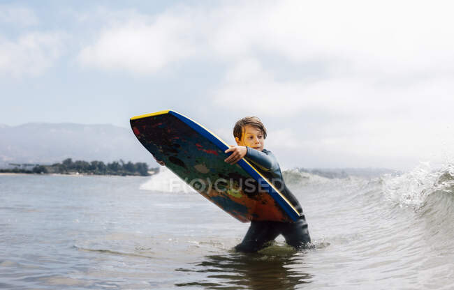Портрет мальчика в мокром костюме в океане, с кузовом в руках, в ожидании волны, Санта-Барбара, Калифорния, США. — стоковое фото