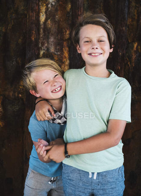Портрет двух улыбающихся мальчиков, обнявших плечо, смотрящих в камеру. — стоковое фото
