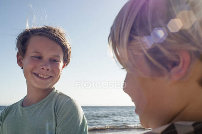Cabeça e ombros retrato de dois meninos sorridentes em pé junto ao oceano. — Fotografia de Stock