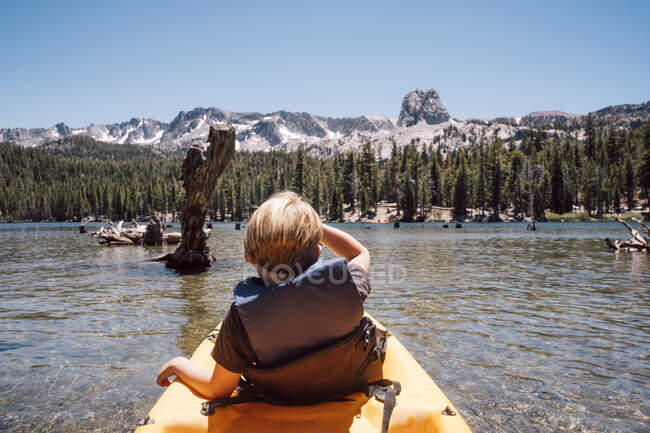 Rear view of boy sitting in kayak on Lake Mary, Mammoth Lakes, California, USA. — Stock Photo