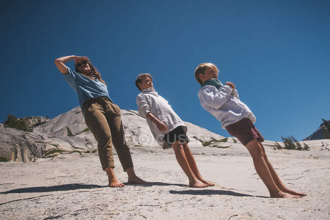 Mujer y dos niños en una visita al Parque Nacional Yosemite, todos inclinados hacia atrás, disparados en un ángulo. - foto de stock