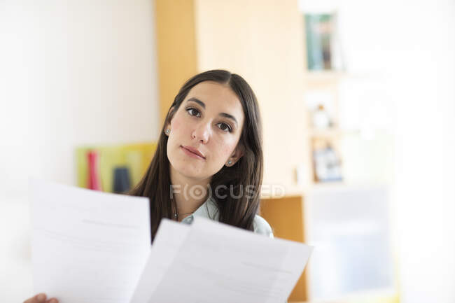Ділова жінка сидить за столом, тримаючи документ — стокове фото