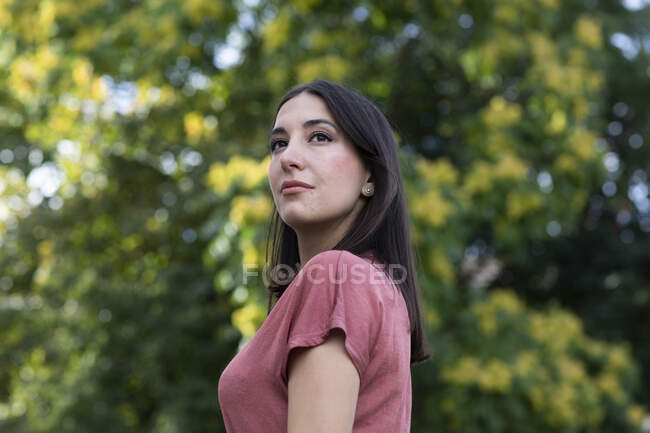 Mujer vistiendo top rosa polvoriento y de pie al aire libre - foto de stock