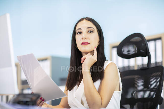 Деловая женщина сидит за столом, держит документ — стоковое фото