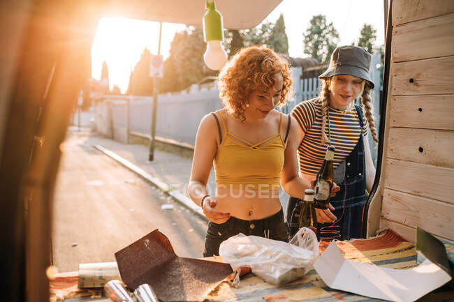 Mujeres jóvenes tomando cerveza detrás de su furgoneta - foto de stock