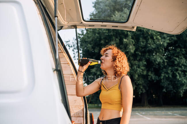 Junge Frau trinkt Bier im hinteren Teil eines Lieferwagens — Stockfoto