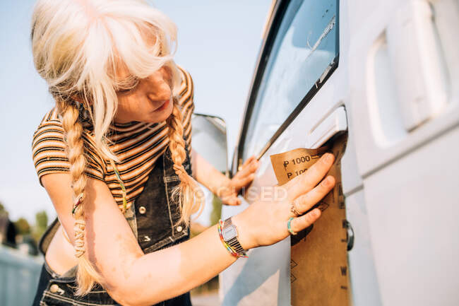 Молода жінка використовує наждачний папір на фургоні — стокове фото