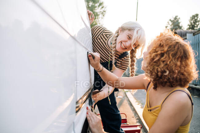 Молода пара-жінка працює на своєму фургоні — стокове фото