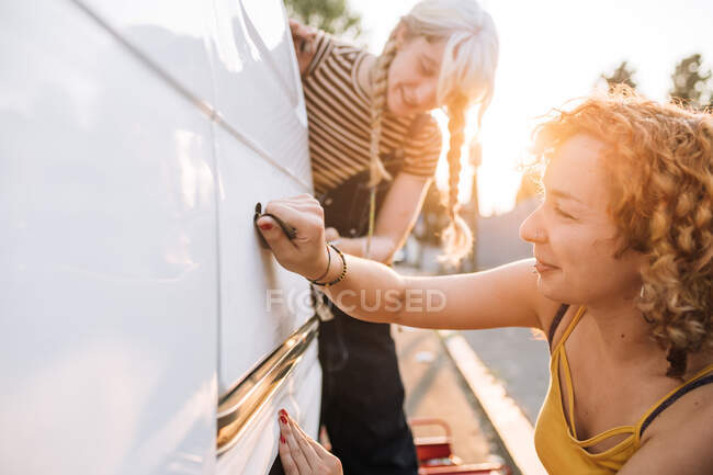 Joven pareja femenina trabajando en su furgoneta - foto de stock