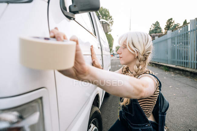 Mujer joven usando cinta adhesiva en su furgoneta - foto de stock
