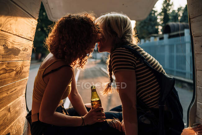 Jovem casal lésbico compartilhando beijo na parte de trás de sua van — Fotografia de Stock