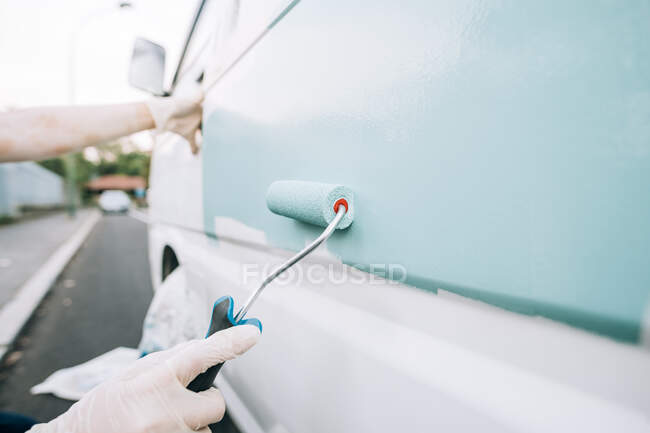 Hands of person painting van with roller — Stock Photo