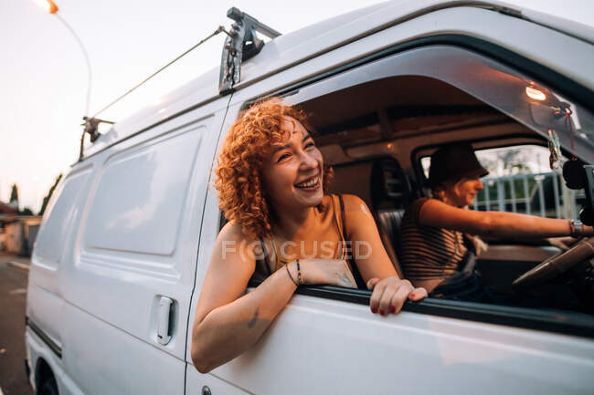Happy young woman leaning out of van window — Stock Photo