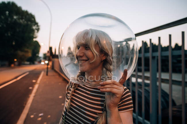 Giovane donna sulla strada con ciotola di vetro sulla testa — Foto stock