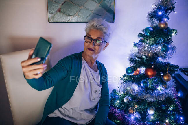 Woman having video call by Christmas tree — Stock Photo