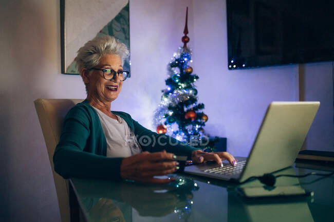 Frau auf Laptop-Videoanruf, Weihnachtsbaum im Hintergrund — Stockfoto