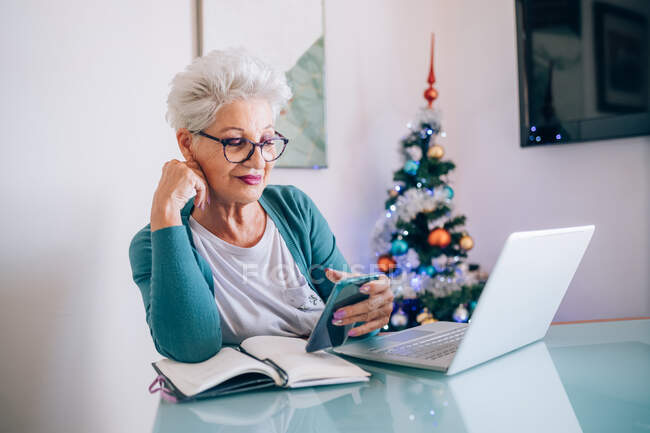 Woman working at home, Christmas tree in background — Stock Photo