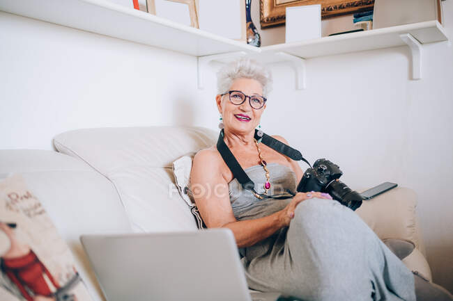 Photographer at home with camera and laptop — Stock Photo