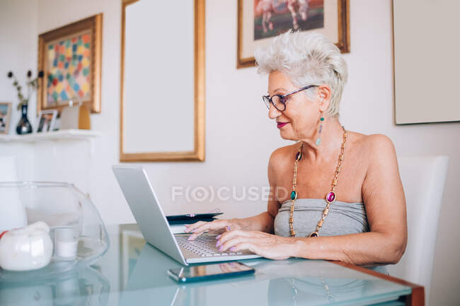 Mujer mayor que trabaja en casa - foto de stock