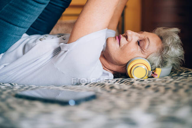 Mujer estirando y escuchando auriculares - foto de stock