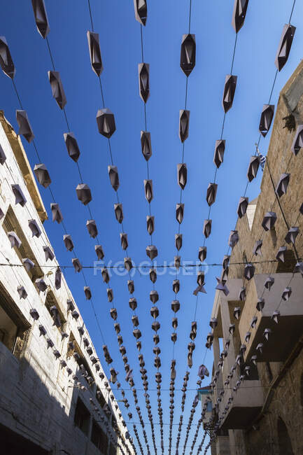 Rows of folded metal boat hats hanging from cables over an alley — Stock Photo