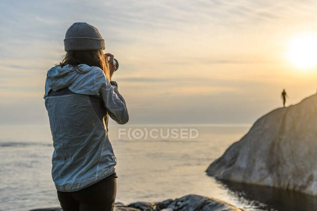 Fotógrafo en la costa, fotografiando amigo en la distancia, Ontario, Canadá - foto de stock